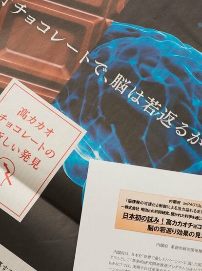 1月21日の日経新聞朝刊に掲載されたカラー広告(上)と18日の記者会見資料。ともに「高カカオチョコレートと脳の若返り」に言及している(撮影/写真部・岸本絢)