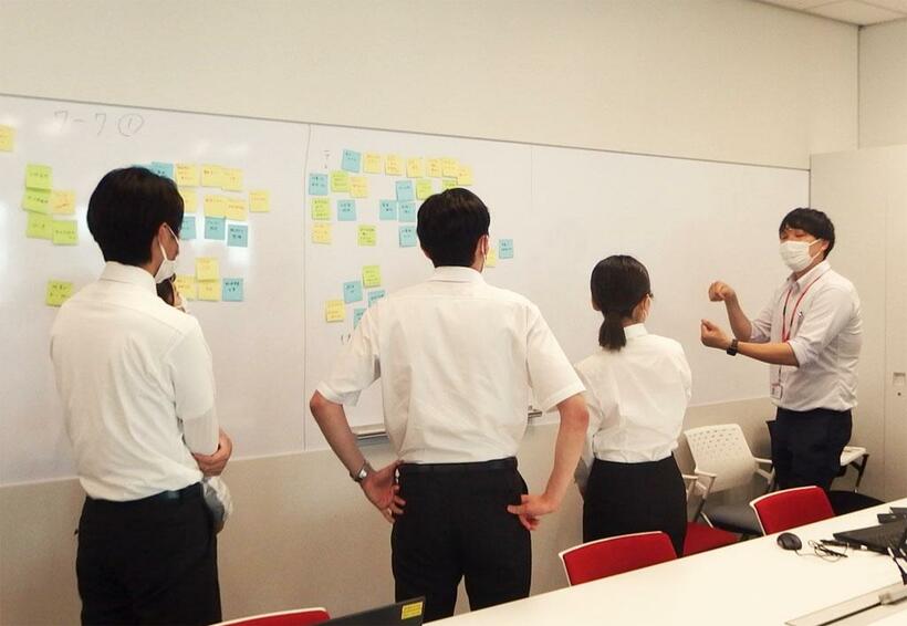 今夏行われた日本郵政・日本郵便合同インターンシップで、人事部の先輩社員（右）とともに課題に取り組むインターンの学生（写真：日本郵政提供）