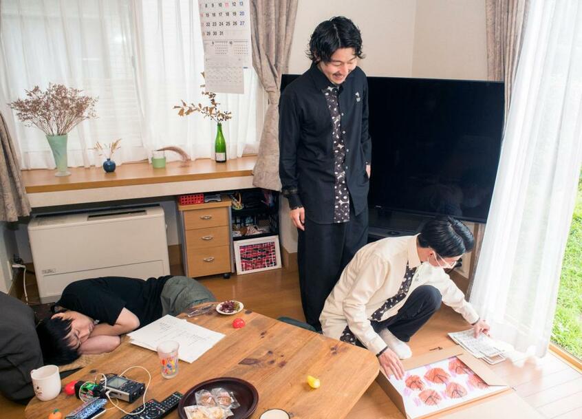 翔太(左)は18歳のときから平日は通所の作業所に通っている。最近描いたコンテ画を見て驚く崇弥(中央)と文登(右)。「翔太さんいい感じじゃん! 素敵な作品だよ!」(崇弥)(写真=横関一浩)