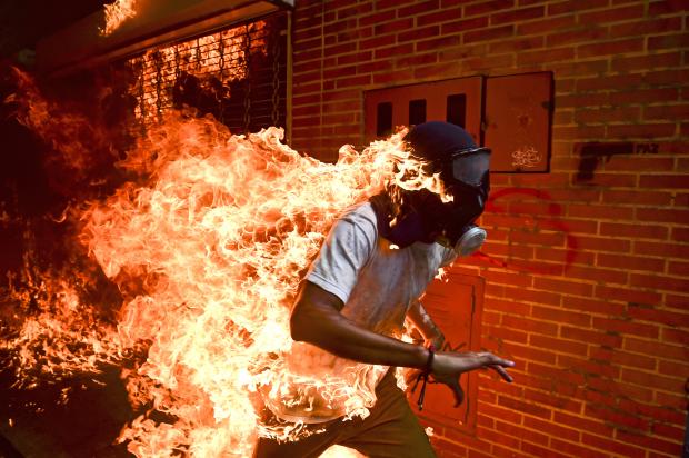 炎に包まれてもなお（ベネズエラ）スポットニュースの部　単写真１位 ロナルド・シュミット（ベネズエラ、ＡＦＰ通信）ベネズエラの首都カラカスでニコラス・マドゥロ大統領に対する抗議デモ参加者が警察機動隊と衝突。青年の着衣に引火し火だるまに