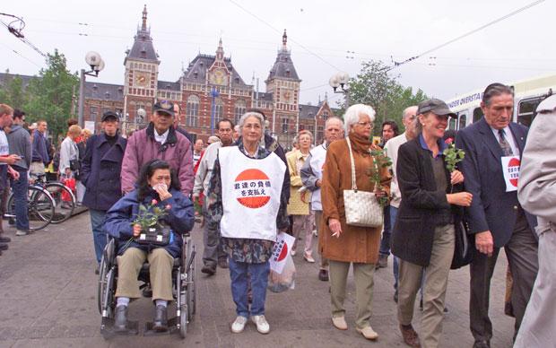日本に補償を求め、アムステルダム中央駅前でオランダ人の日本軍抑留被害者らが「父母を返せ」などとデモ行進した／２０００年５月２３日　（ｃ）朝日新聞社