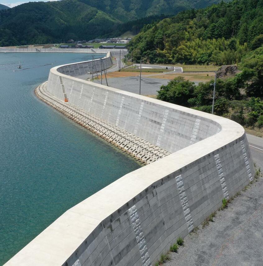 延々と続く雄勝湾の防潮堤。中央の空き地付近に６４人の犠牲を出した雄勝病院があり、高橋頼雄さんの自宅もすぐ近くだった。奥には高台移転地も見える　（ｃ）朝日新聞社