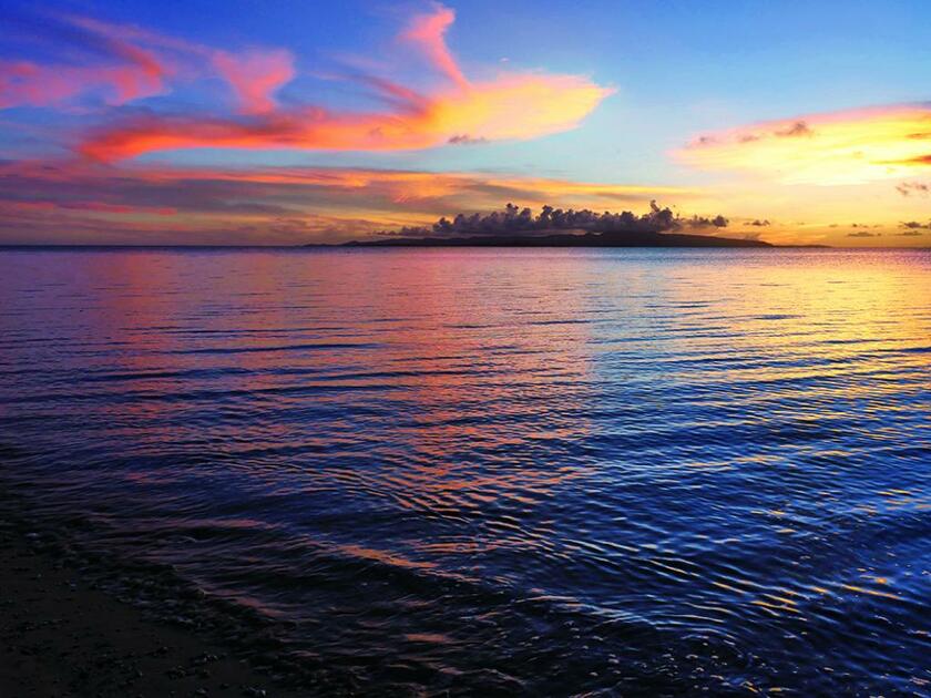 石垣島・フサキビーチ付近からは東シナ海に沈む夕日を望める。正面に西表島のシルエットが浮かび、鮮やかな夕焼け色が八重山の夏を感じさせてくれる　■パナソニックLUMIX GH4・LUMIX G X VARIO12～35ミリF2.8 II ASPH. / POWER O.I.S.・ISO200・絞りf8・AE