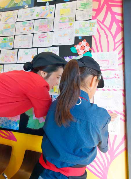 マクドナルド三春町店の壁一面に貼られた色とりどりの塗り絵たち。店舗内で子どもが描いたものだ（撮影／高井正彦）