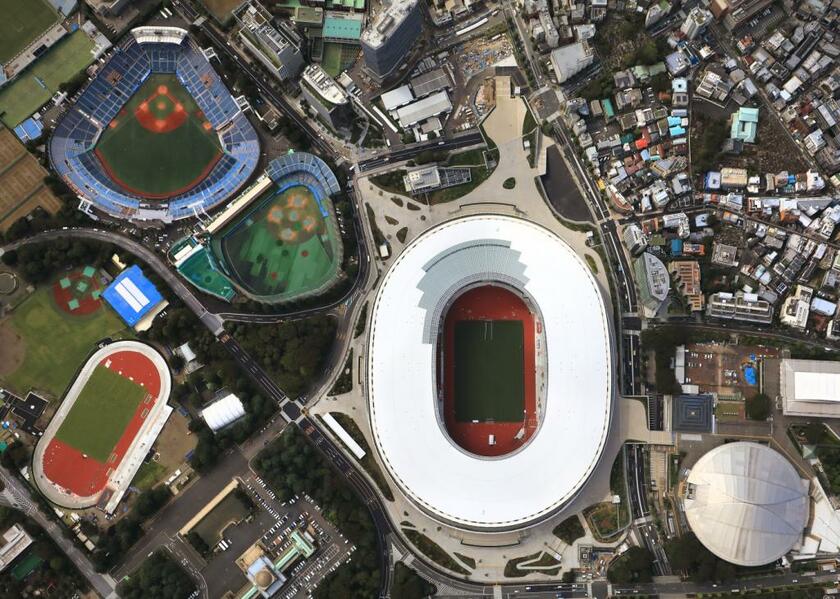 国立競技場の空撮。神宮の杜に浮かび上がるようにドーナツ形の白い屋根がひときわ目を引く。ＴＯＫＹＯ２０２０はここから動き出す（撮影／写真部・小林修）