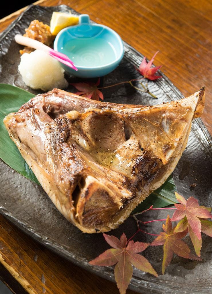 鮪喜（つなき）　まぐろあご焼き／上質な天然本マグロの刺し身をはじめとする鮮魚が、豊洲の鮪問屋直営ならではの良心的な価格で味わえる。骨ごと香ばしく焼いた「まぐろあご焼き」（８８０円）は、あごの周りについたコラーゲンたっぷりの身に思わず箸が伸びる。酢でさっぱりと、味噌でピリッと味の変化が楽しめ飽きさせない。ハマグリの殻で中落ちをこそげ落として食べる「鮪の骨付き中落ち」（１４８０円～）や刺し身を豪快に盛った「鮪喜盛り」（３８８０円）など、忘年会にもおすすめの品が揃う。税別　（撮影／写真部・小山幸佑）