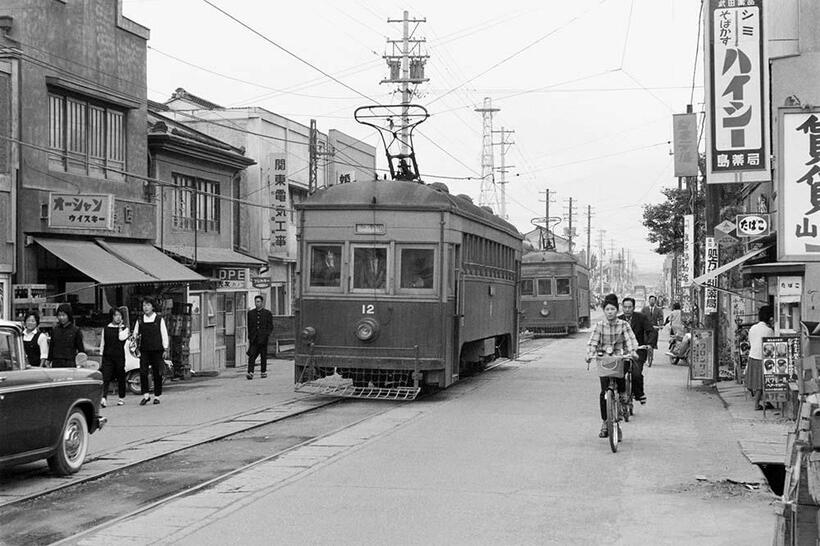 市内目抜き通りを続行運転する浅間線の電車。歩道もない路上は多くの通勤・通学者で賑わっていた。写真のデハ12は1929年日本車輛製で、かつてはオープンデッキ、トロリーポール集電だった。学校前～市民会館前（撮影／諸河久：1963年9月21日）