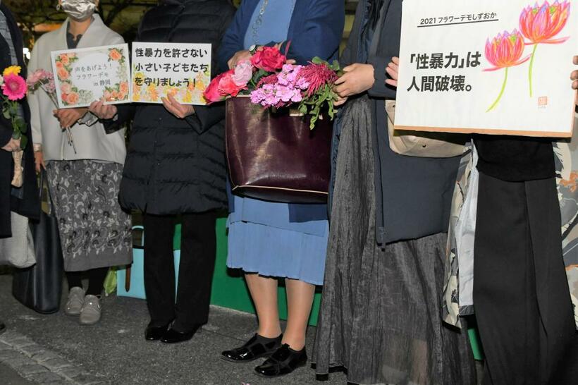 「『性暴力』は人間破壊」などと書かれたカードを持って街頭に立つフラワーデモの参加者たち／２１年１１月