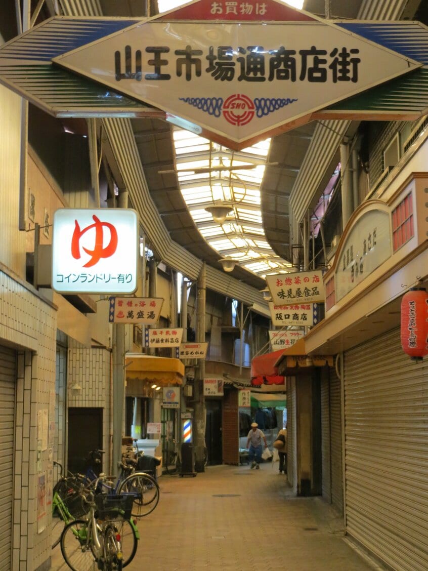 大阪府大阪市「山王市場通商店街」/西成区の再開発が進んでいないエリアにごっそりと残る昭和。「山王市場通商店街」のド渋なサインと緩くカーブした屋根のデザインもいい(撮影/山本有)