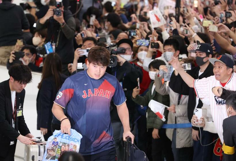 成田空港で大勢のファンの出迎えを受ける日本代表「侍ジャパン」の村上宗隆選手。右のユニホーム姿の男性は記事にも登場する増井さん