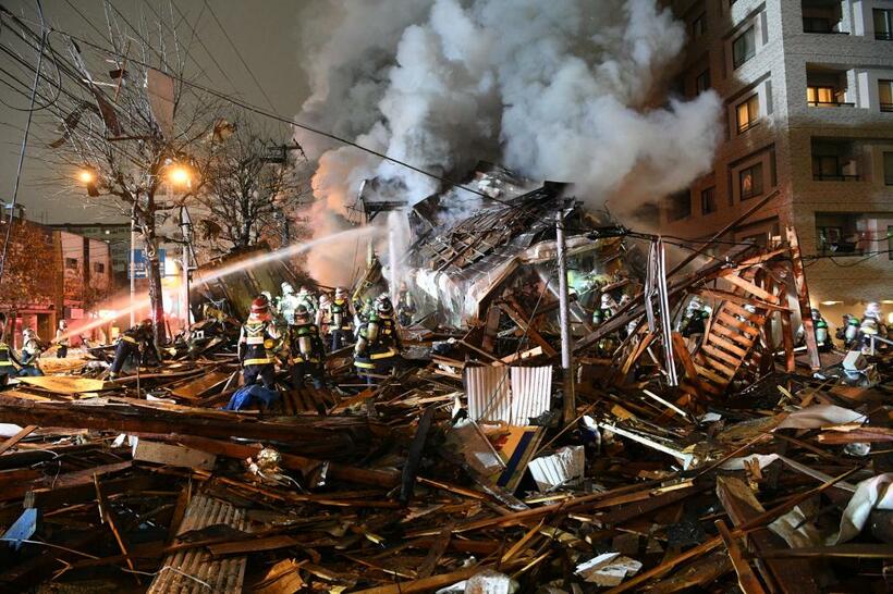 建物が倒壊、炎上した現場。建物は跡形もなく吹き飛ばされ、消防隊員らが消火や救助活動にあたっていた　（ｃ）朝日新聞社