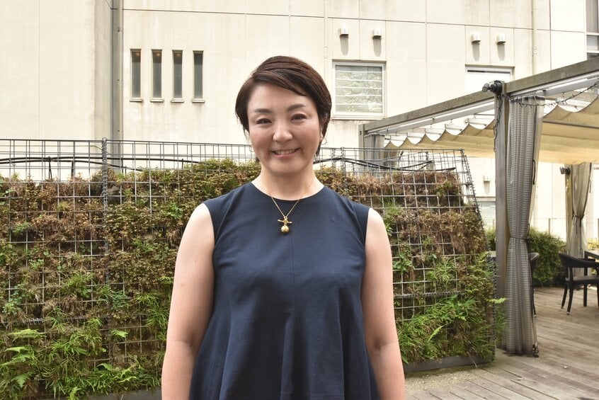 取材の待ち合わせ場所に紺色のノースリーブのツーピースで現れた河井あんりさん。有罪判決の確定後は外出できず、家族が買ってきたケーキを食べ続けた結果、4年間で20キロも太ったという。レストランではトンカツを選び、「共食い」と言って笑った＝2025年7月、東京都内、大崎百紀撮影