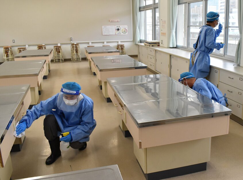 休校中の小学校で、消毒液をつけた布で机や窓ガラスをふく作業員ら=2020年9月30日、広島県