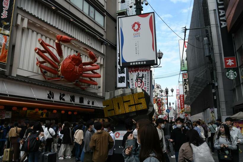 にぎわう大阪市中央区の道頓堀。２０２５年大阪・関西万博を周知する看板がかかる＝２０２３年３月１６日