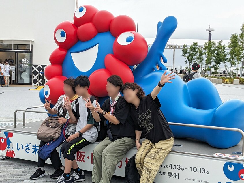 寝そべりポーズのミャクミャクと記念撮影=米倉昭仁撮影
