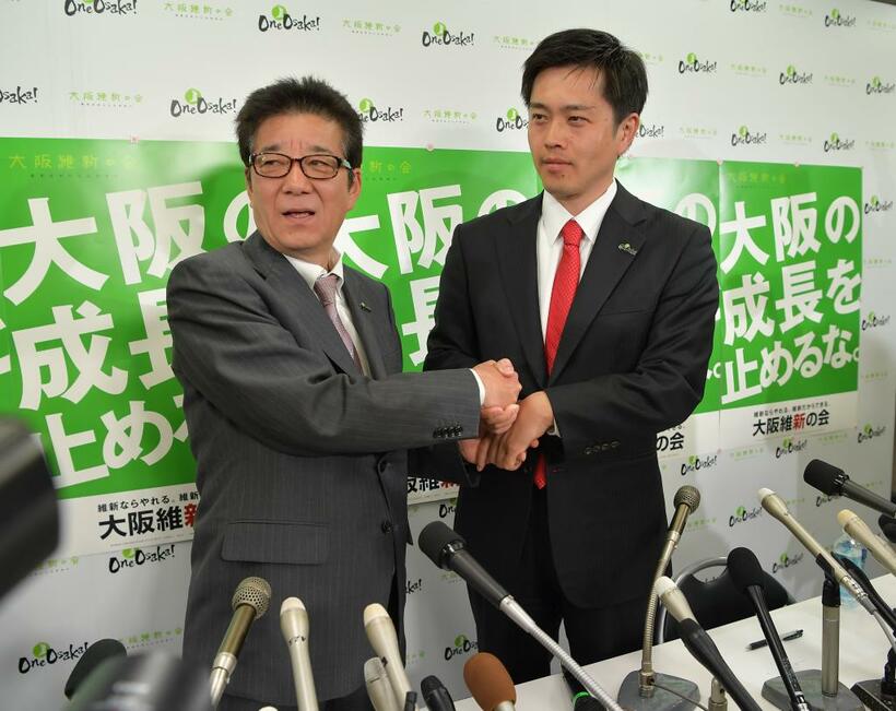 7日、大阪府知事と大阪市長のダブル選で当選を決め、握手する松井一郎氏（左）と吉村洋文氏（ｃ）朝日新聞社