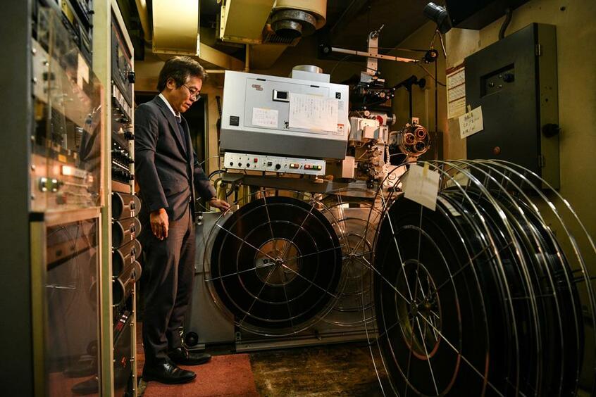 「時代時代で、いろんなタイプの作品を上映しました。世代によってうちで見た映画が違い、思い出も異なるのではないでしょうか」とフィルムを前に語る興行部の加藤和人さん　（撮影／写真部・馬場岳人）