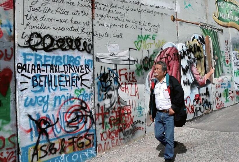 イスラエル西岸地区の分離壁の前を歩く。後藤和夫監督は、監督作で自ら主人公としてパレスチナを訪れた。上映日などの情報は公式ホームページまで（写真：後藤監督提供）［ｈｔｔｐｓ：／／ｎｉｐｐｏｎｐｏｐｋｙｏ．ｗｉｘｓｉｔｅ．ｃｏｍ／ｐａｌｅｓｔｉｎｅ］