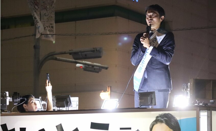 斎藤氏の演説を撮影する折田氏(左下)