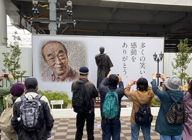 東村山駅前の志村さんの銅像前で写真撮影するファンたち