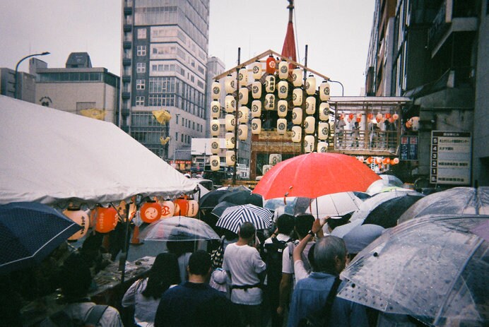 人ごみを避けて雨の中進む時に、ヒョイと傘をあげて進む瞬間、赤い傘が祇園祭のアクセントに