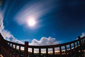 石垣島バンナ展望台で夜8時ごろ、フィッシュアイ16ミリF3.5で約30分露光。満月で空が明るく、眼下には市内の明かりが写り込み、昼と夜が一緒になったような不思議な写真だ