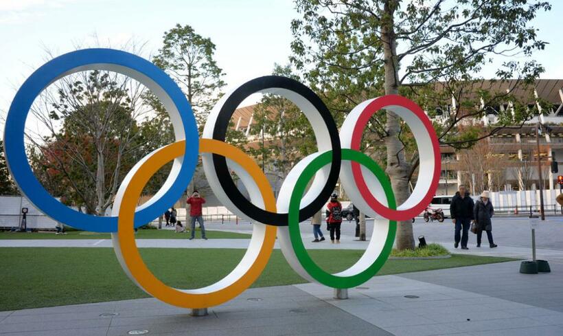 「ジャパン・スポーツ・オリンピック・スクエア」の前にある五輪のモニュメント。後ろは東京五輪・パラリンピックの主会場となる新しい国立競技場＝東京都新宿区、撮影・多田敏男