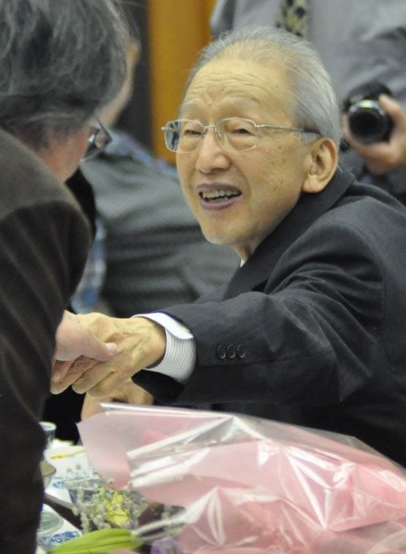 米寿を祝う会で仲間と握手をする吉田さん＝同