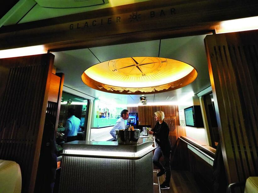 エクセレンスクラスの車端にあるグレッシャー・バー。列車の中とは思えないゴージャスでシックな空間である。天井にはプラネタリウムにも似た羅針盤があり、マッターホルンやヴァイスホルン、リスカム、ドームなど、氷河特急の沿線の名峰が描かれている。名酒の棚には信州の清酒「真澄」も■オリンパスOM－D E－M1 MarkII・7～14ミリF2．8・絞りf5・ISO6400・AE・＋0．7補正・JPEGスーパーファイン（撮影／櫻井寛）
