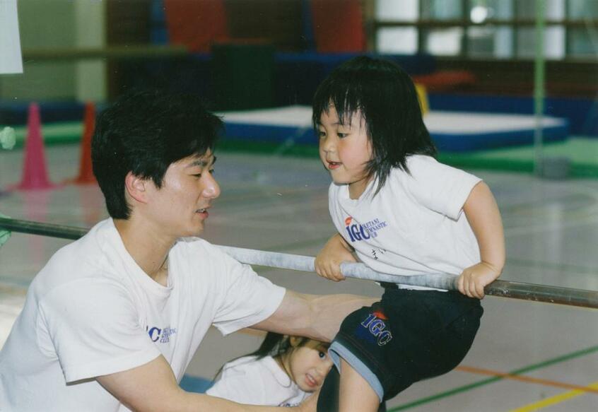 父・仁さんと鉄棒の練習をする幼少期の村上茉愛=母・英子さん提供 (c)朝日新聞社