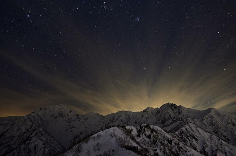 「星夜の五竜岳・鹿島槍ケ岳」。遠見尾根の西遠見山でひとり雪洞を掘り終えると、すでにあたりは暗くなり星が瞬き始めていた。やがて満点の星空になるころ、北アルプスの稜線から放射状に雲が伸びてきて、朝にはどんよりした空になってしまった■ニコンZ 6・ニッコール Z 200mm f/1.8 G・ISO1250・絞りf2.5・15秒