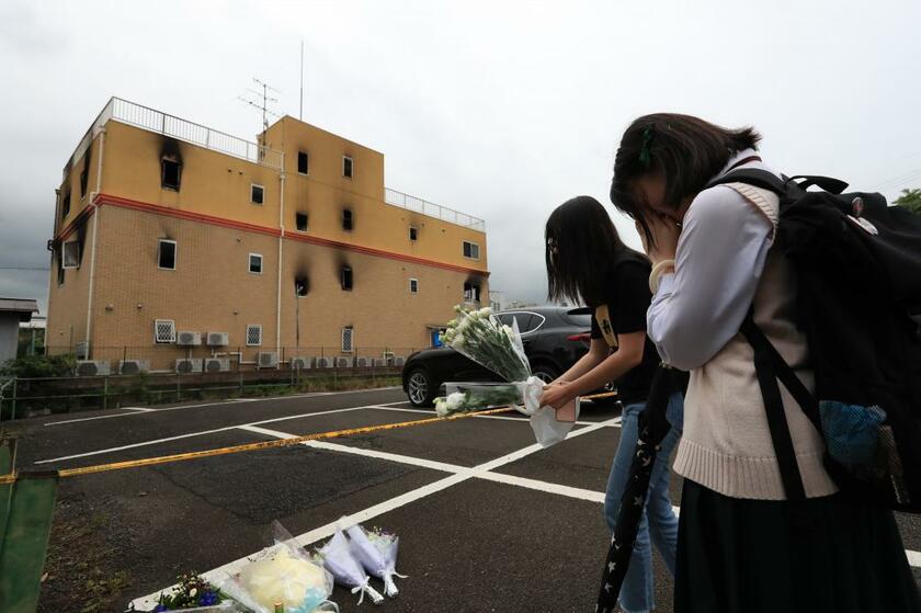 燃えた建物の前で追悼する人たち　（ｃ）朝日新聞社