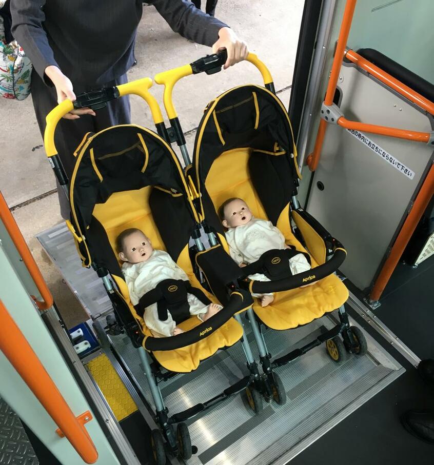双子の人形を使ってのバス乗車の研修。タラップが組み込まれているバスであれば、ツインベビーカーでも負担なく乗車できる。困ったときは乗務員に「助けて」と声をかけることも大切だ(写真・あいち多胎ネット提供)