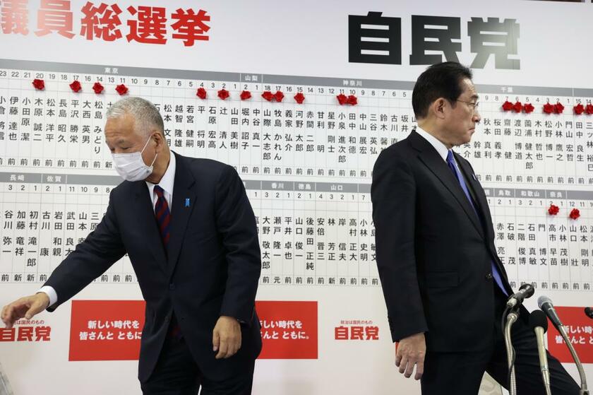 浮かない表情で当選者に花をつける甘利幹事長と岸田首相（C)朝日新聞社