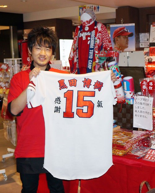 ４年前に特注した黒田のユニフォームを持つ横山さん。アンテナショップに入荷した「黒田グッズ」は、発売３時間半ほどでほぼ完売（撮影／編集部・内堀康一）
<br />