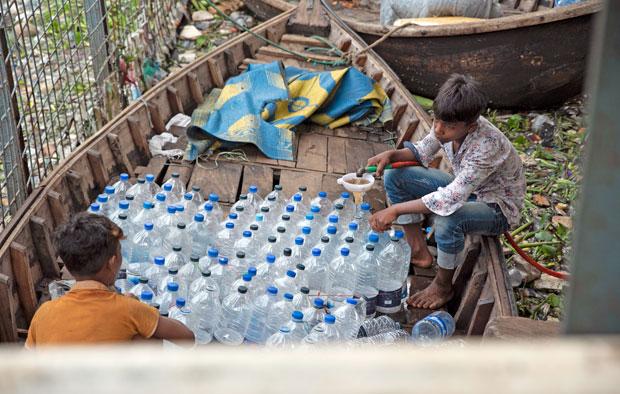 早朝、拾い集めたペットボトルに水道水を入れる少年たち。船着き場などで売り歩く（撮影／フォトグラファー・清水匡）