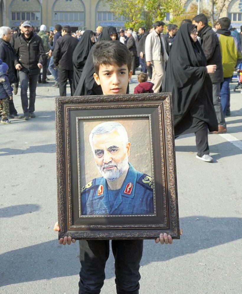米軍に殺害されたイラン革命防衛隊のソレイマニ司令官の肖像を持つ子ども＝テヘラン　(c)朝日新聞社　