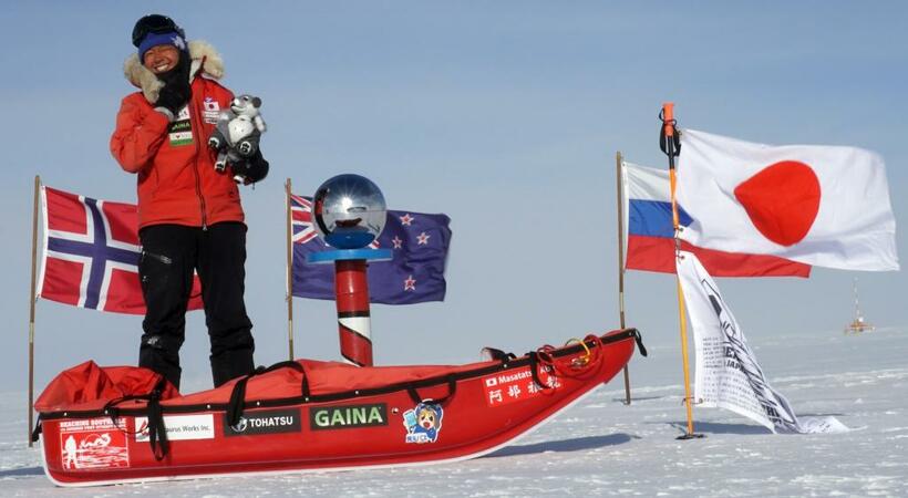 南極点に到達した阿部雅龍さん。日の丸のほか、各国の国旗が立っている＝人力チャレンジ応援部提供
