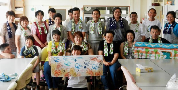 工房地球村のメンバー。首にかけているのは「いちごものがたり」の手ぬぐい。