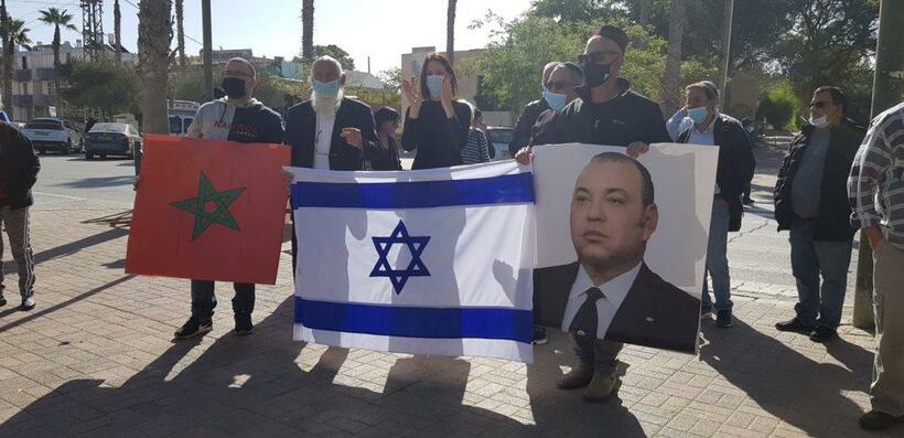 モロッコのリーダーの肖像とイスラエル国旗を持つモロッコ系ユダヤ人＝エルサレム市内で（ニシム・オトマズキン提供）