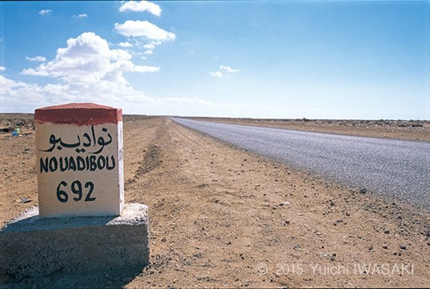 ヌアディブまで692キロメートルと示す道標。アルファベットとアラビア文字で併記されている。　西サハラ　2001年／West Sahara 2001