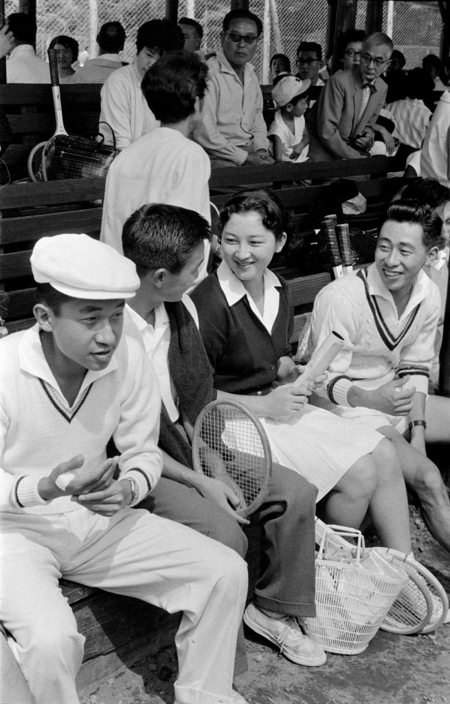 1958年、軽井沢で行われたトーナメント会場のテニスコートのベンチで、出場者と談笑する正田美智子さん。左は皇太子さま（Ｃ）朝日新聞社