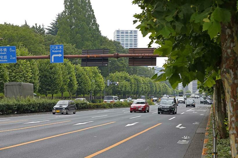 拡幅された現在の青山通り（国道246号線）。背景の赤坂御用地と街路樹の緑が梅雨空に映える。画面中央に30階建ての「赤坂Kタワー」が見える。青山一丁目（撮影／諸河久：2019年7月13日）