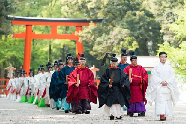 参進する黒い斎服の宮司以下、奉仕者の列が続く。鮮やかな赤や青、そして白い装束や、一つひとつの細やかな所作が平安朝の伝統を今に受け継ぐ（撮影／写真部・馬場岳人）