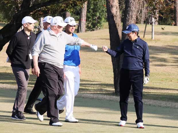 ゴルフ中にグータッチをする安倍晋三首相（右）とトランプ米大統領（中央）　＝内閣広報室提供