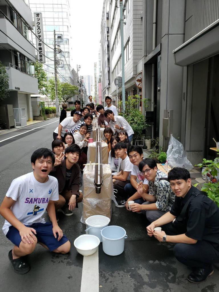 コロナ前の「大学のお水飲み比べサークル」の活動風景。大学の水を使い、流しそうめんを食べ比べた。左側２列目が代表の茂木さん（茂木さん提供）