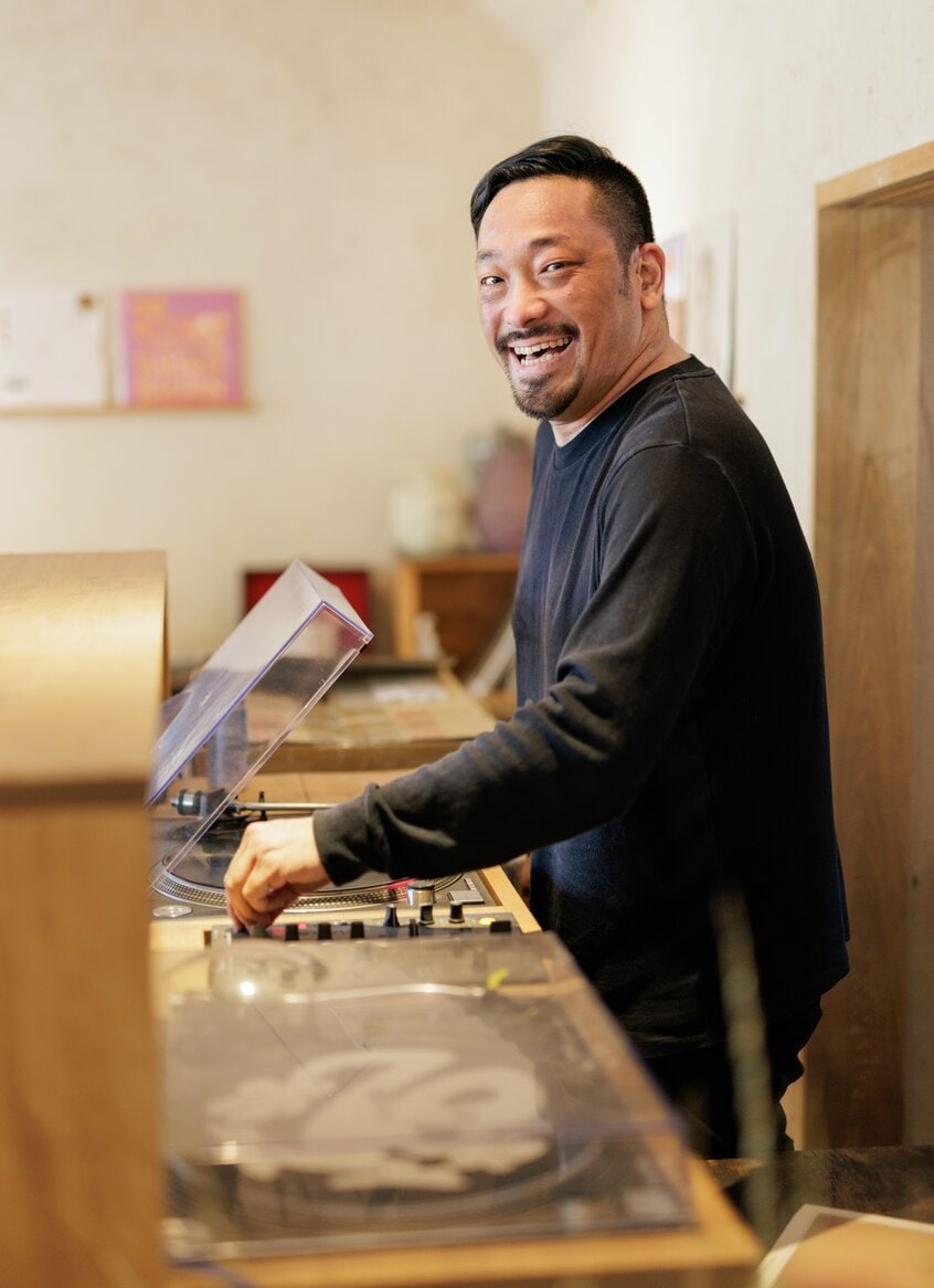 DJブースで「Rapt In Fantasy」(石野卓球)を流し始めるとこの笑顔。岡が経営する「ONE RECORD STORE」で(写真/山本倫子)