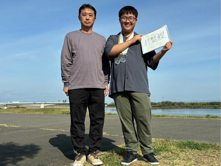 「漢検スーパー中学生」の角鹿脩斗さん（右）と父・哲弥さん。メダルは「日本漢字能力検定協会賞」（金紐）と「特別賞」(銀紐)。掲げた超難読漢字は「うぐえ」と読み、魚を捕る道具を意味するそうだ。