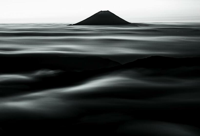 南アルプス・千枚岳で。夜明け前の富士山。東の薄明の空を背景に、雲海を前景にシャッターを開けた。露出は約6分。長時間の露出で雲がゆったりと流れた。左の稜線に富士スバルライン五合目の明かりが見える　■ニコンD810・AF-Sニッコール50ミリF1.8G・ISO250・絞りf5・372秒