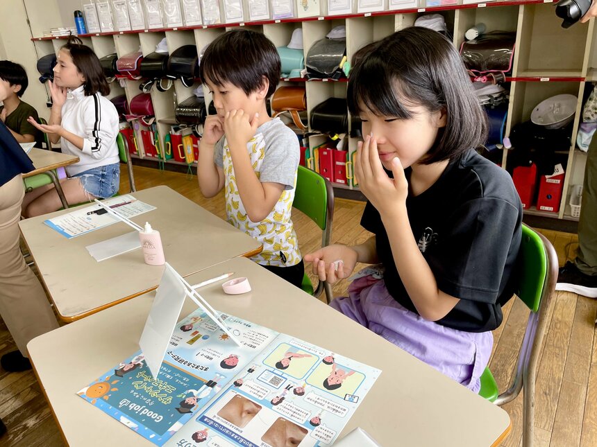 鏡を見ながらクリームを塗る子どもたち